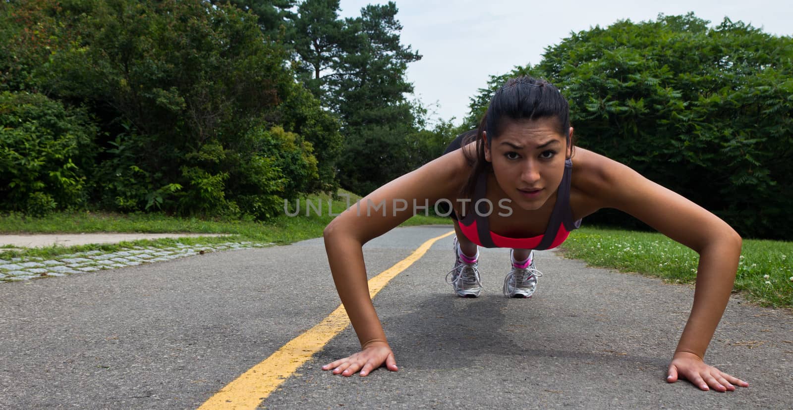 Fit young woman doing push-ups outdoors by bigjohn36