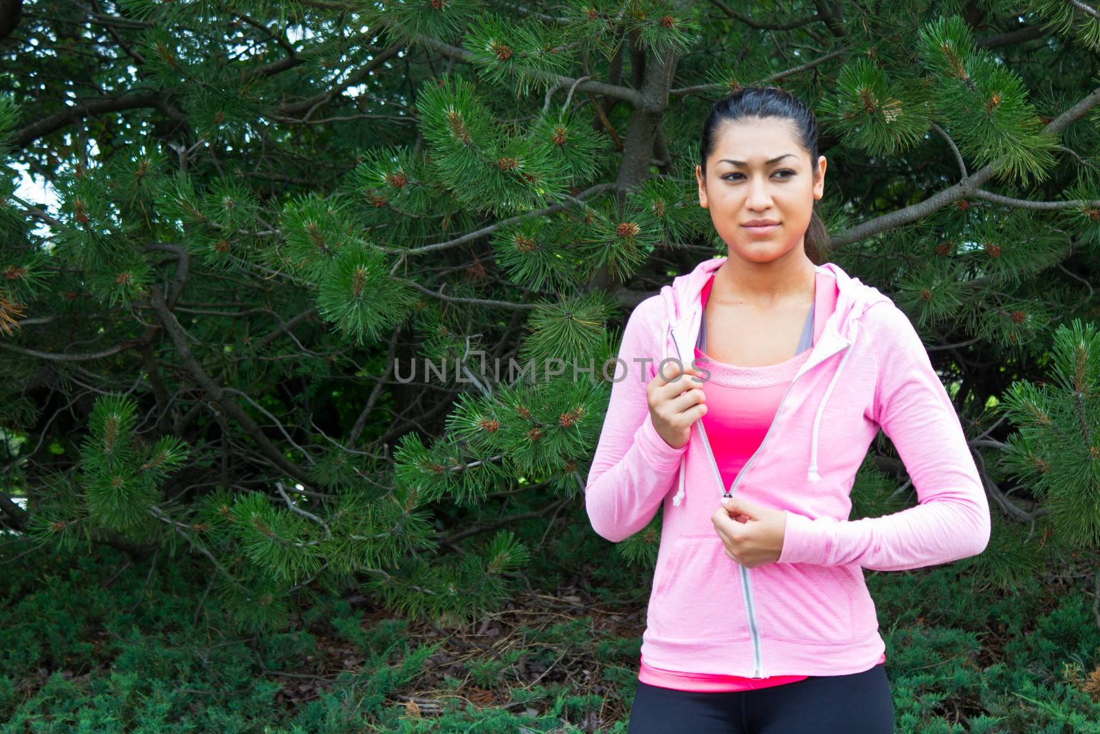 Young woman removing her jacket before a workout
