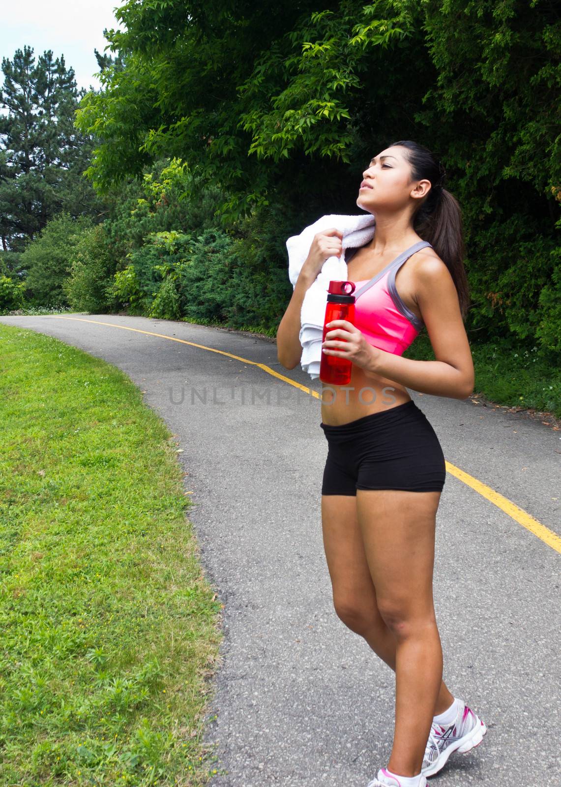 Young woman resting with towel and water bottle after running