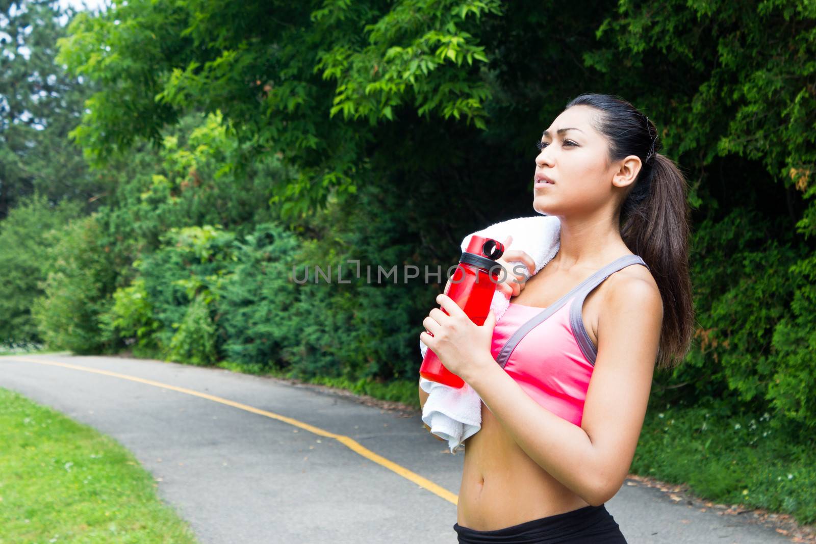 Young woman resting with towel and water bottle after running