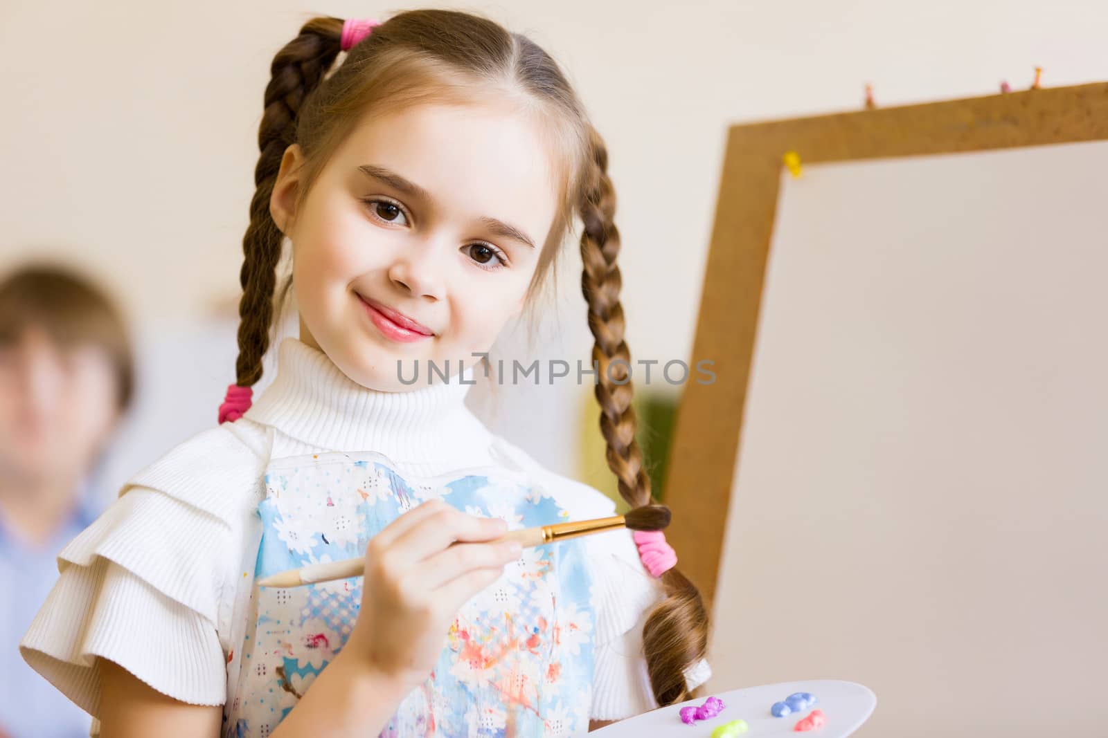 Little cute girl with paint brush and easel