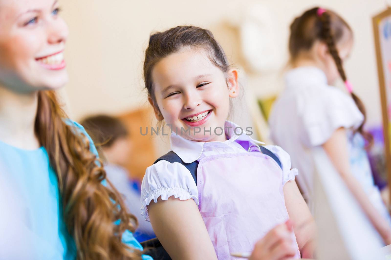 Little girl painting with teacher at kindergarten