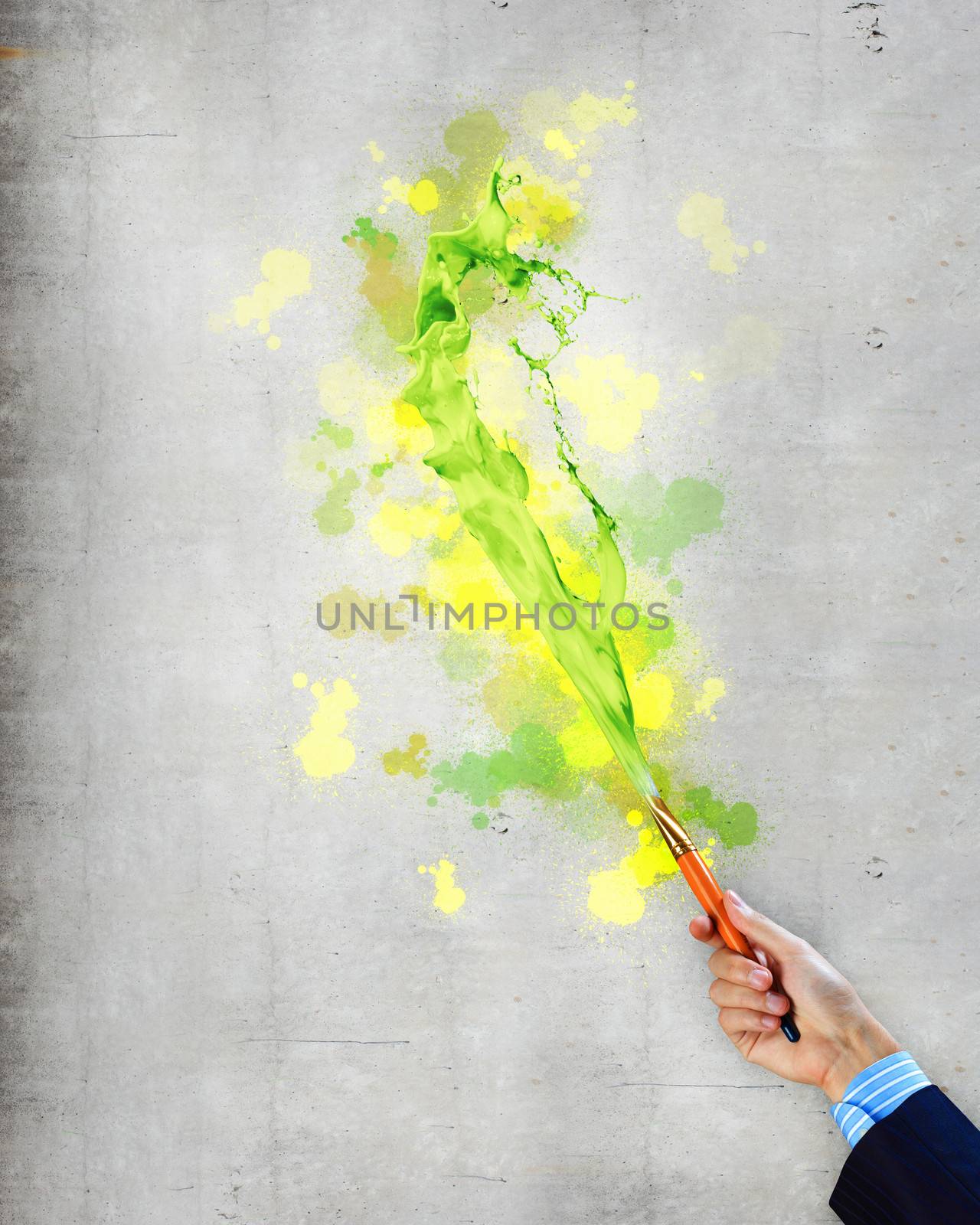 Close-up of human hand holding paint brush making colorful paint splashes