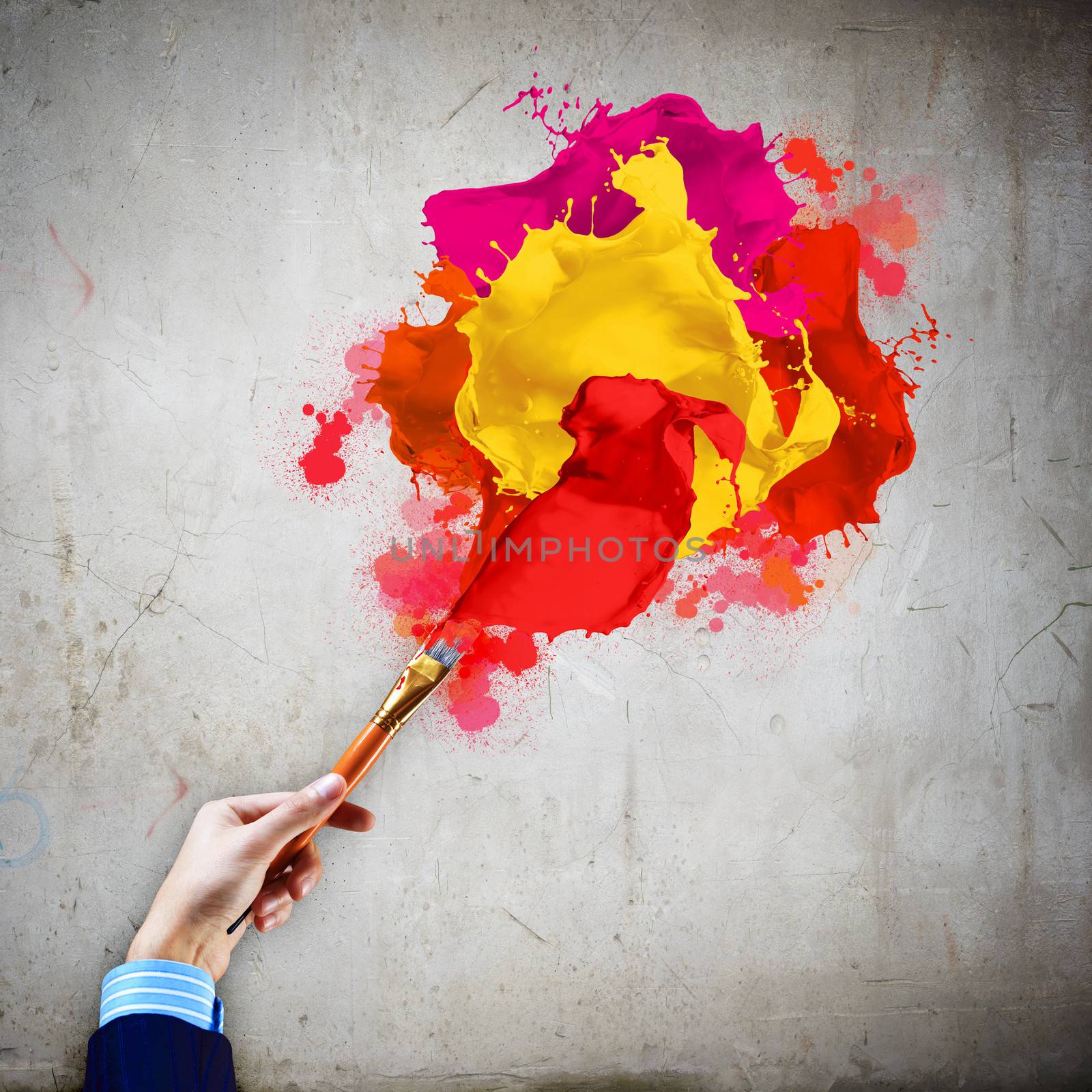 Close-up of human hand holding paint brush making colorful paint splashes