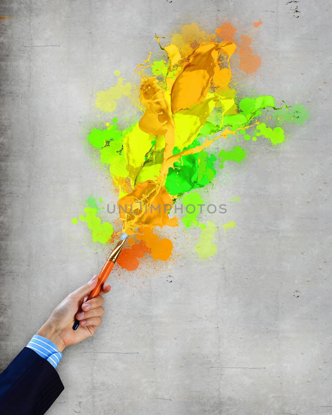 Close-up of human hand holding paint brush making colorful paint splashes