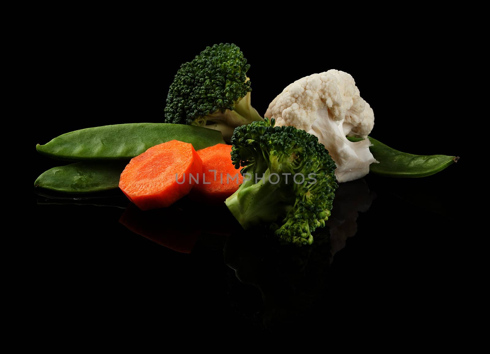 Fresh carrot, green peas, broccoli and cauliflower on the black background