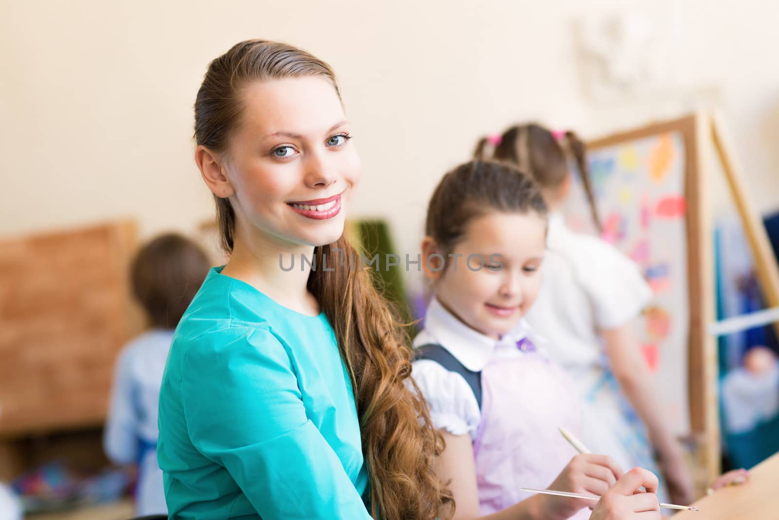 children with the teacher engaged in painting at an art school