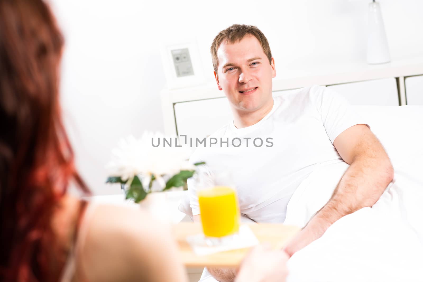 woman brought her boyfriend breakfast in bed, holding a tray of juice and breakfast