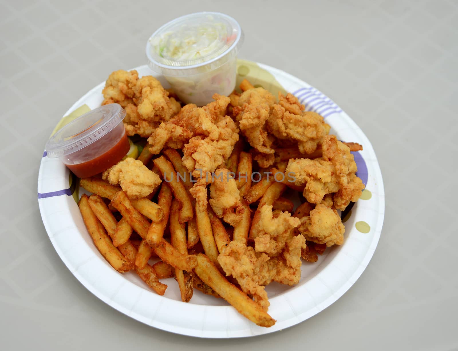 fried conch fritters with coleslaw and french fries on a paper plate