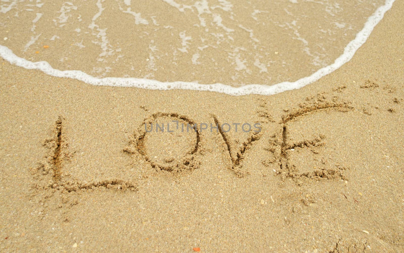 Love written in the sand in a warm tropical beach