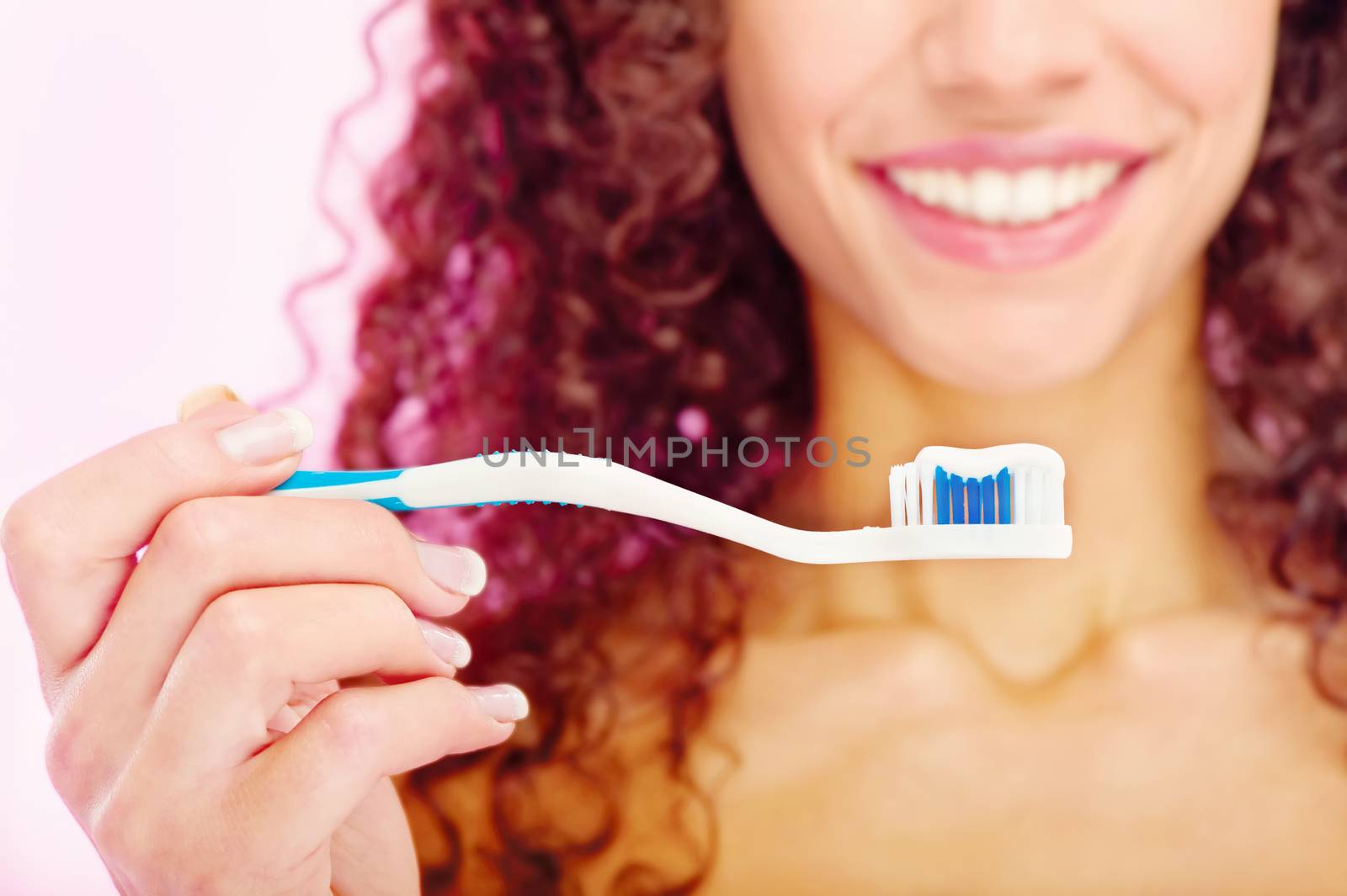  close up of a teeth brush and girl's smile behind