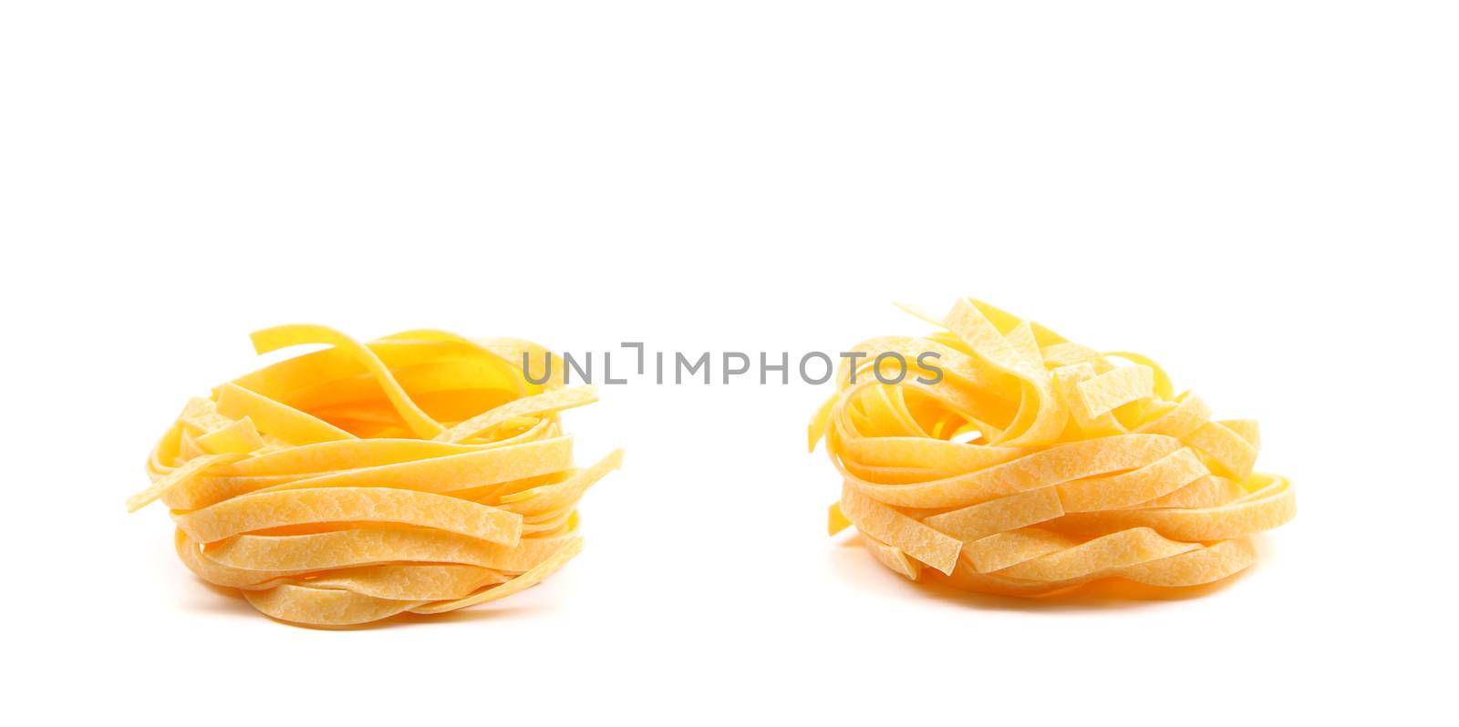 Two fettuccini pasta nests isolated on white. Close up.