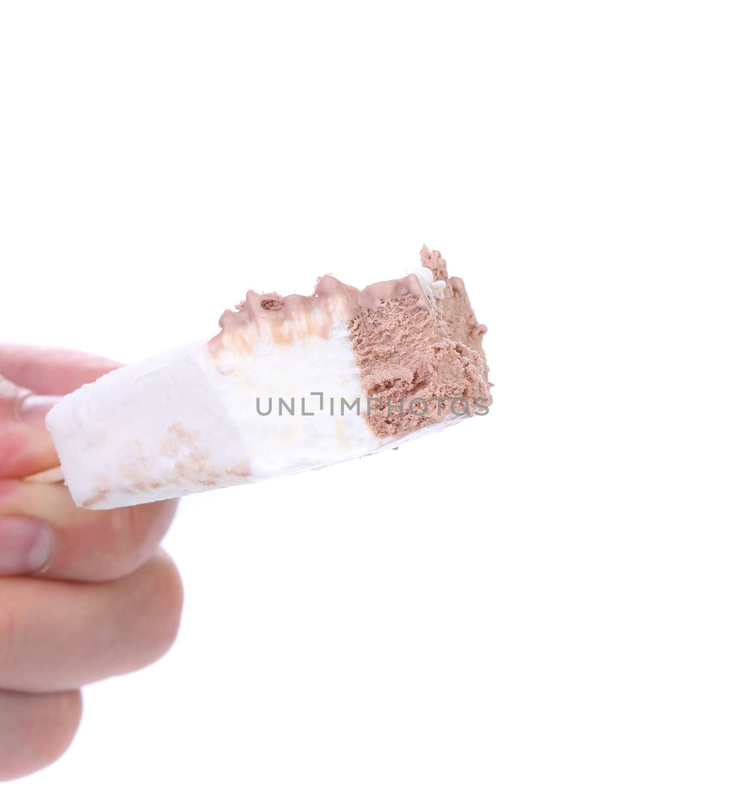 Hand holds bitten vanilla and chocolate ice cream. White background.
