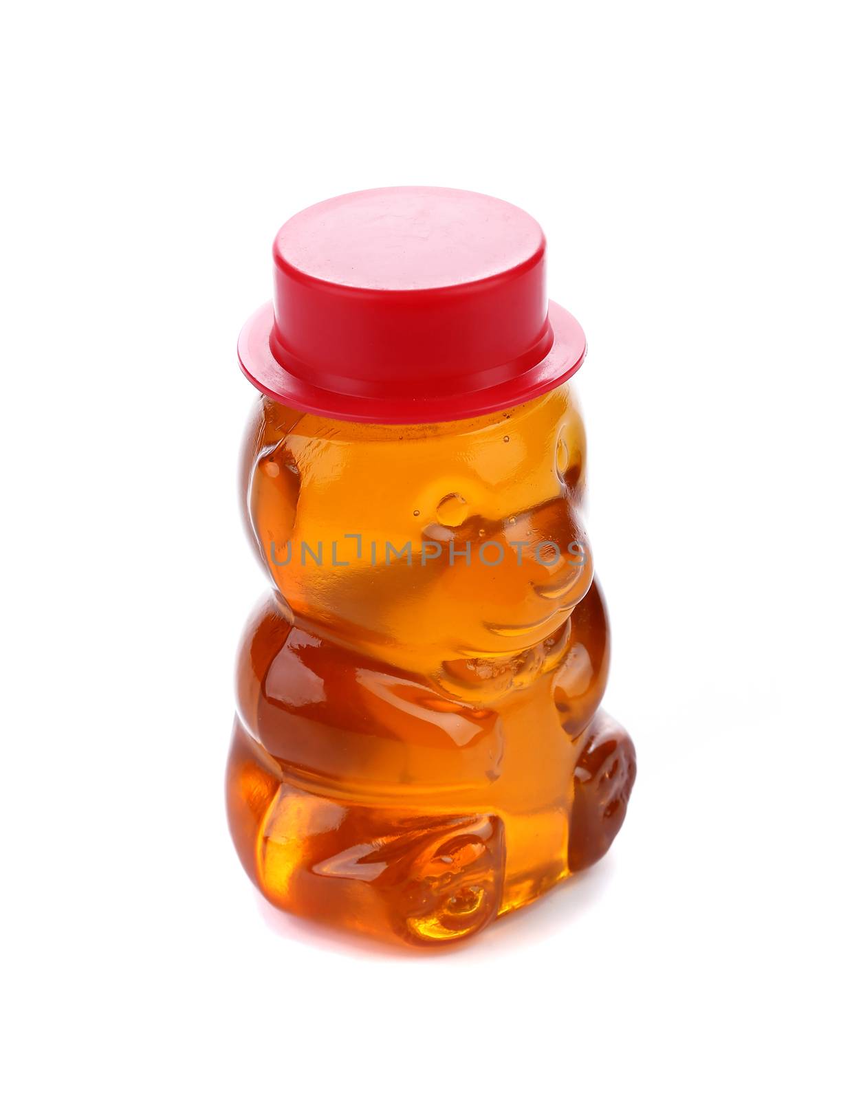 Bottle shaped like a bear and filled with honey. White bckground.