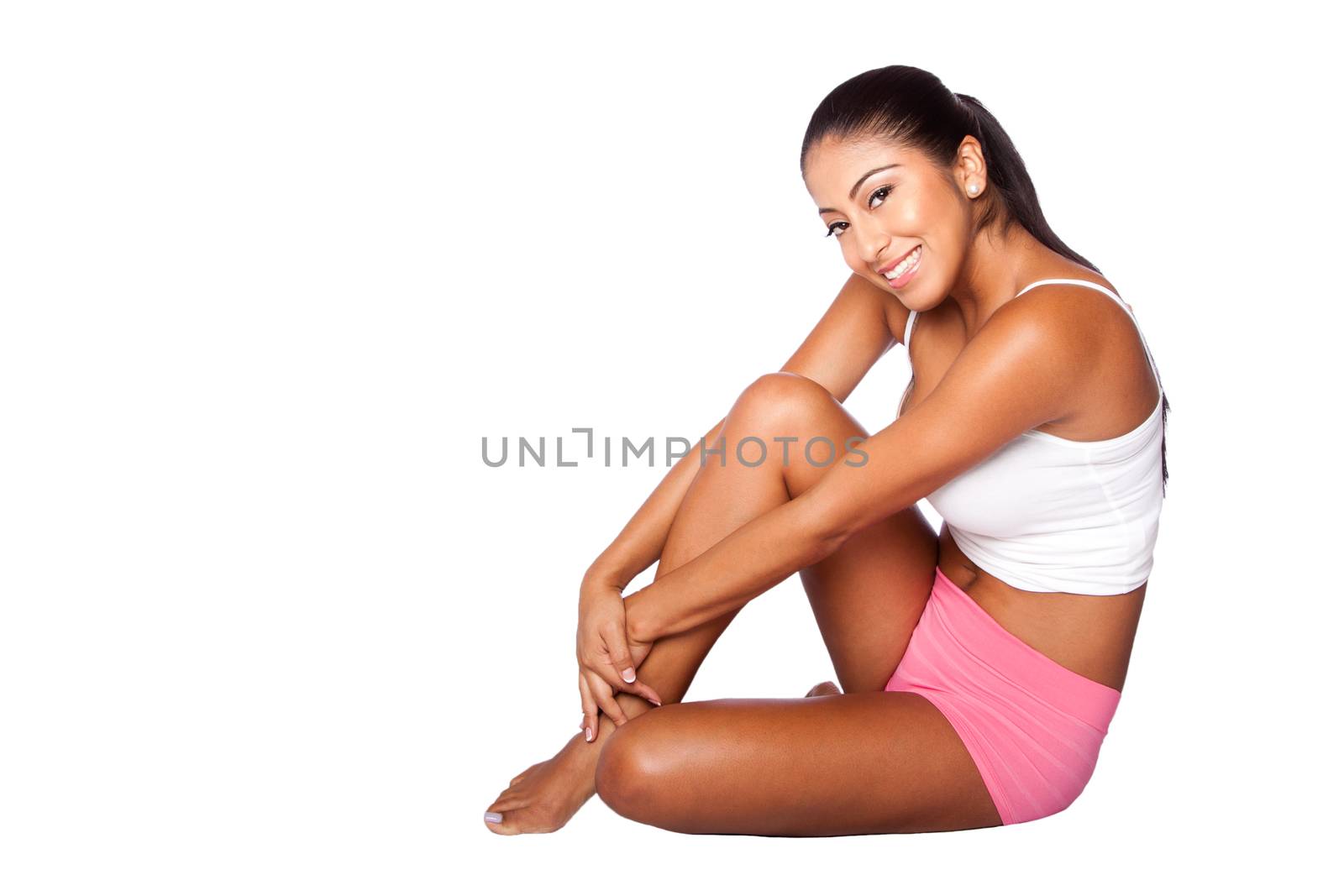 Beautiful happy smiling healthy young woman with radiant skin sitting on floor wearing sporty clothes, bodycare concept.