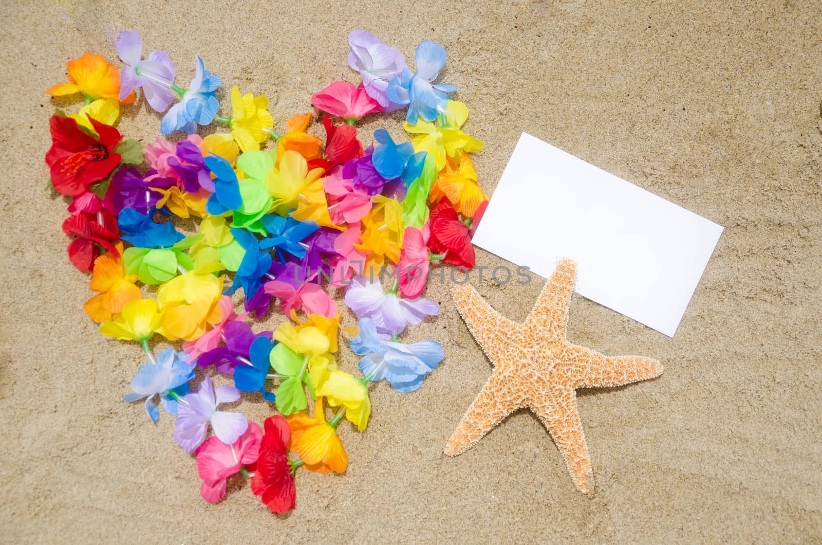 Heart shape of the Hawaiian flowers, starfish and white card on the beach