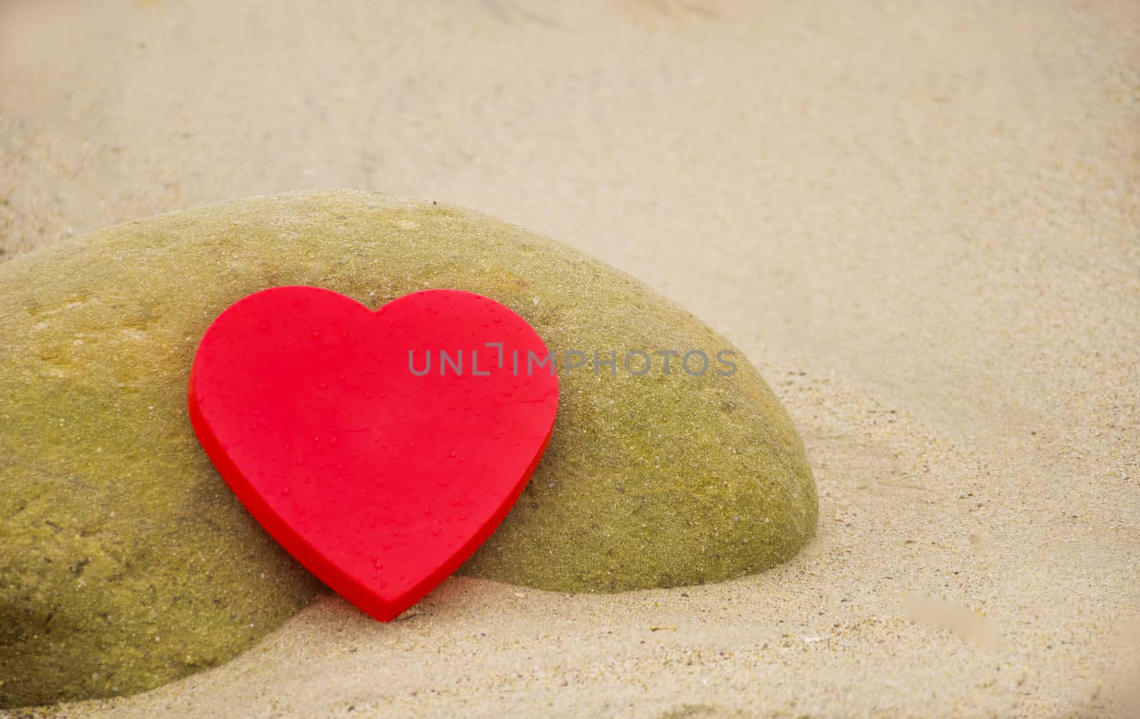 Red Heart shape by the rock on sandy beach