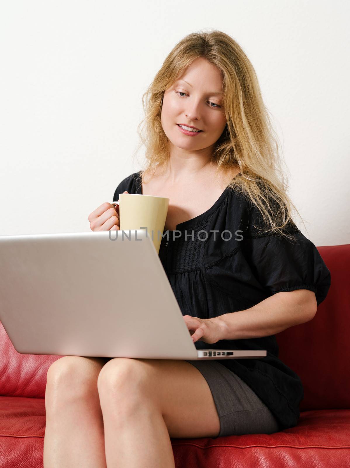 Photo of a beautiful young female shopping online and drinking coffee at home.
