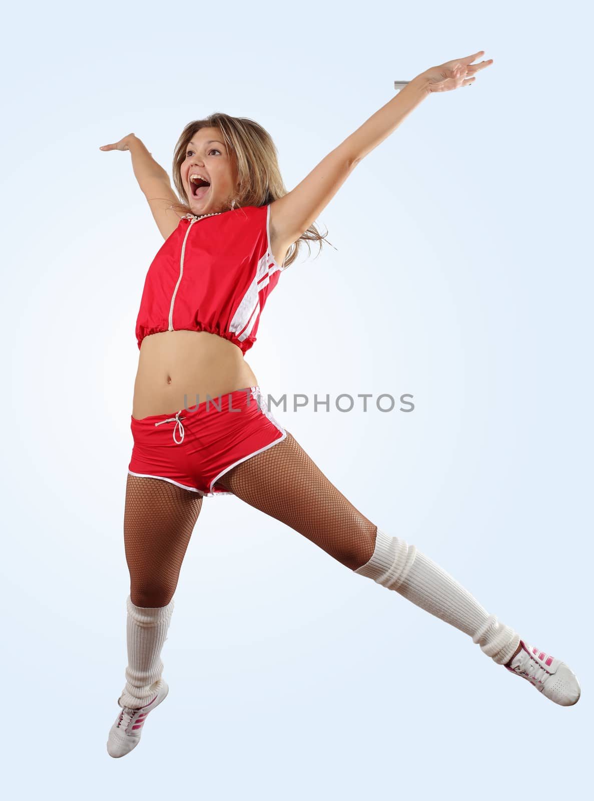 Uniformed cheerleader jumps high in the air isolated on white.