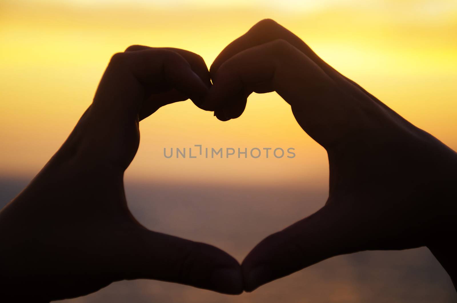 Silhouette of hand in heart shape on sunset in Malibu