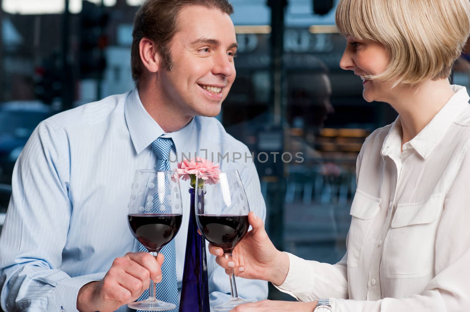 Attractive love couple toasting red wine in open-air cafe.