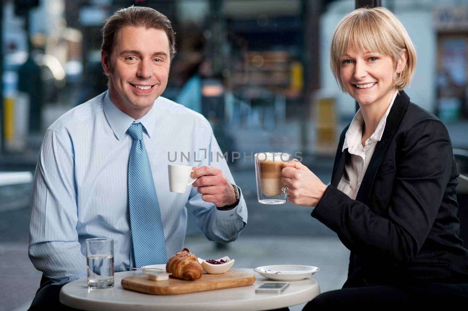 Two corporates discussing business over snacks by stockyimages