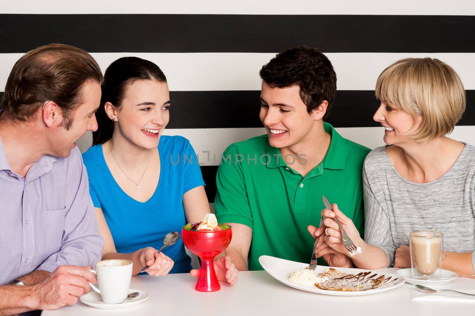 Cheerful family of four relishing delicious eatables and dessert.