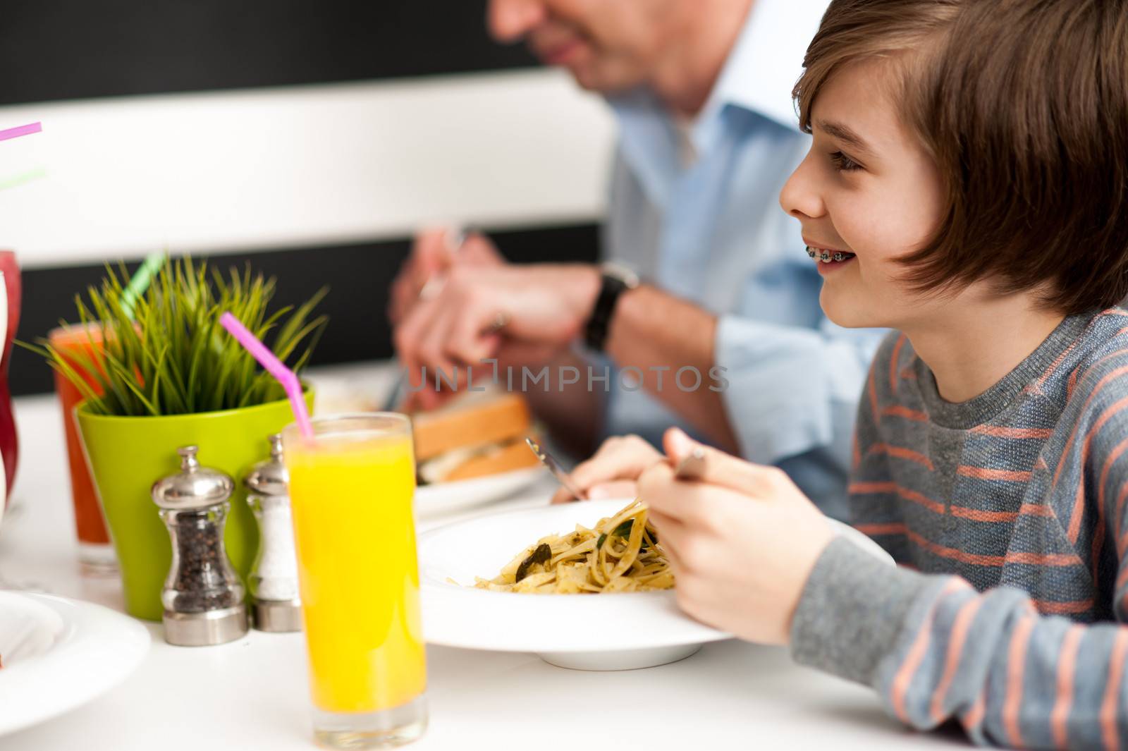 Cheerful son with his dad enjoying breakfast at restaurant.