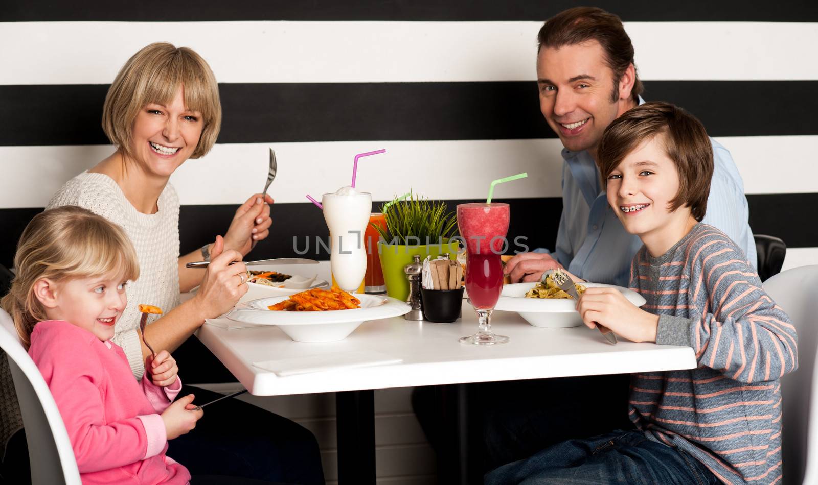 Father and mother with children enjoying meal in restaurant.