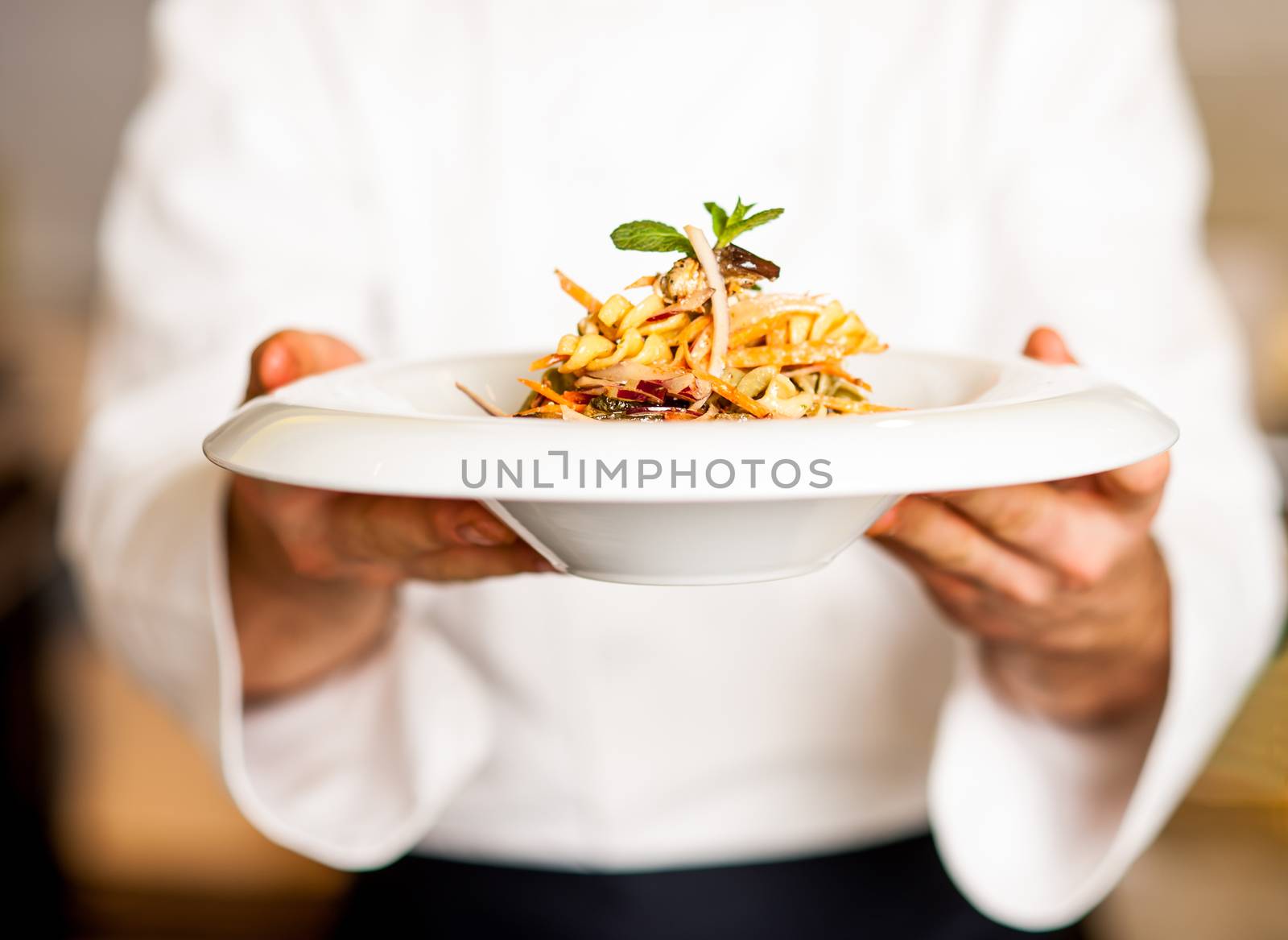 Chef offering pasta salad to you by stockyimages