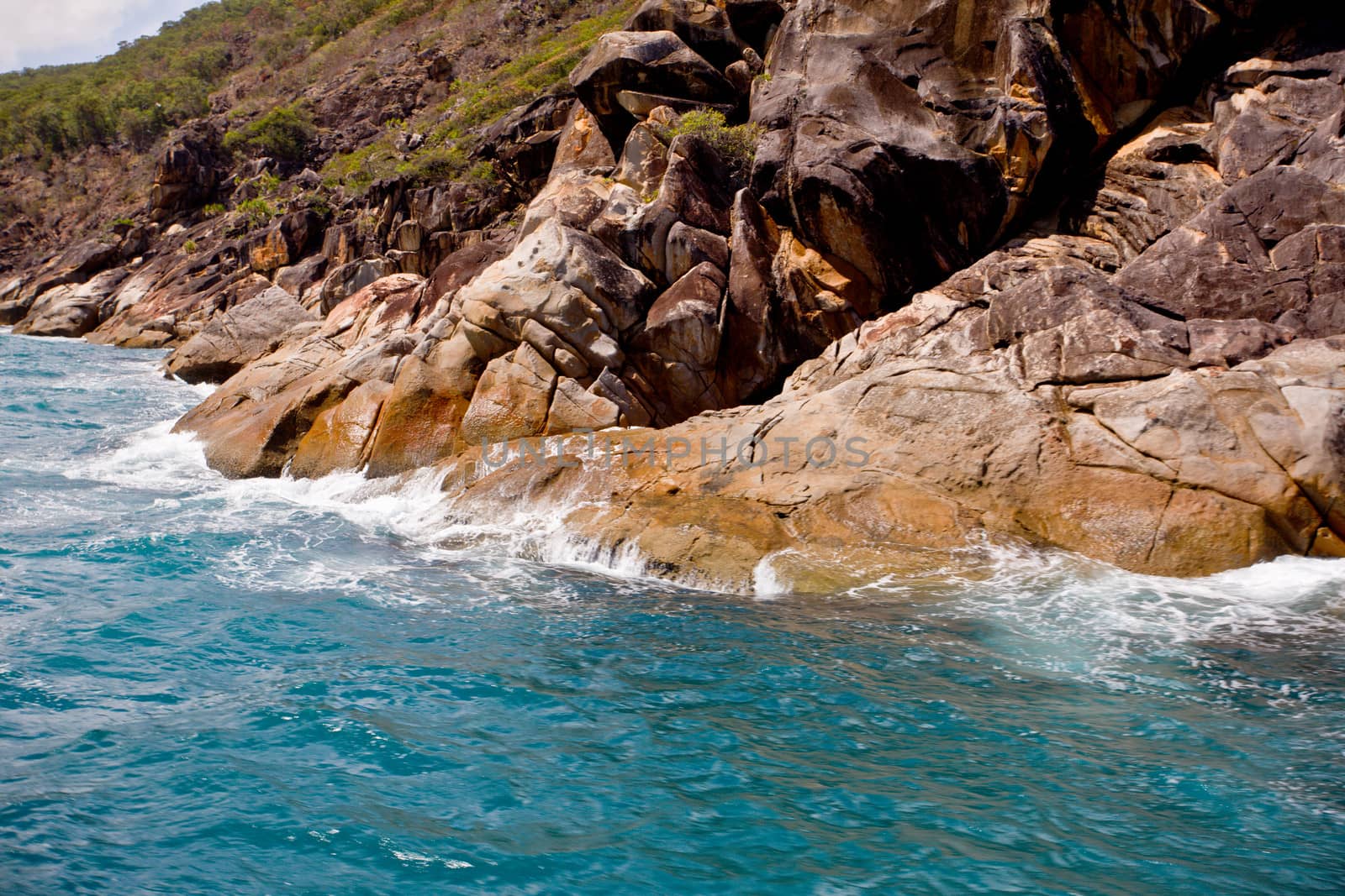 View from the ocean of gentle waves breaking on a rocky shoreline on the Australian coast