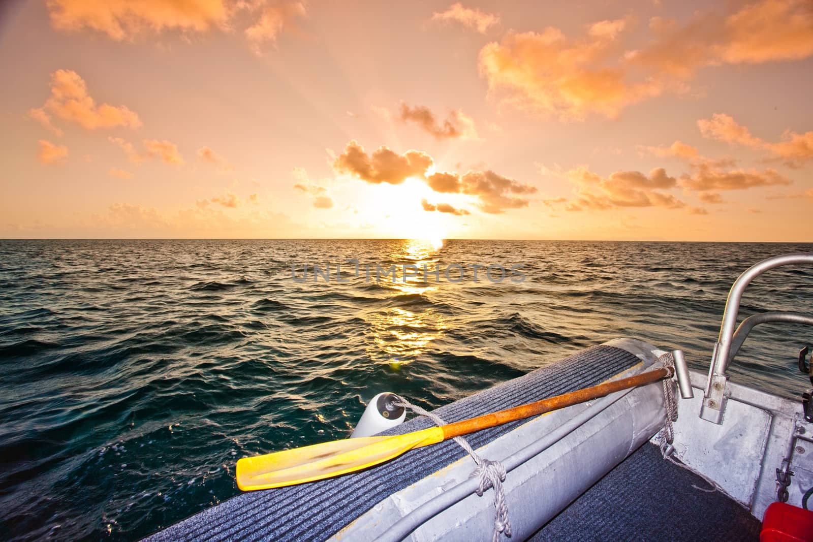 Spectacular orange ocean sunset as the sun dips below the horizon seen from the deck of a rigid inflatable in mid ocean