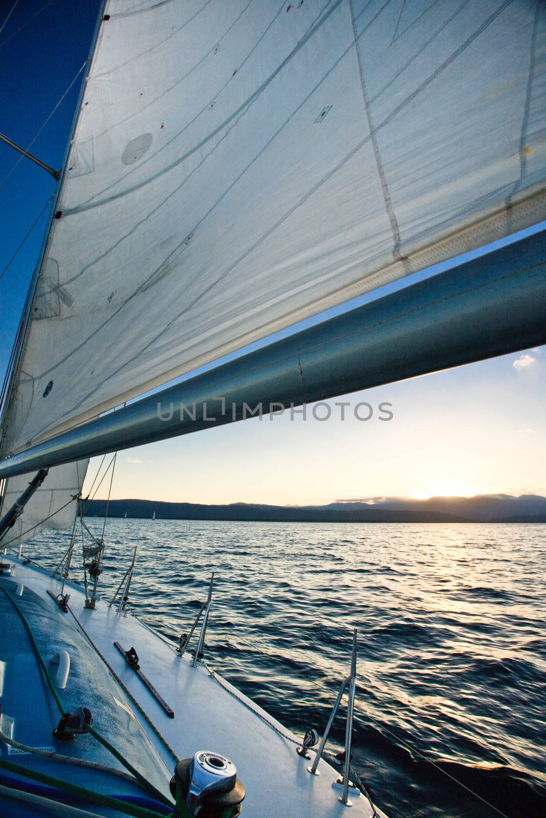 Sunset over the ocean from the deck of a yacht sailing mid ocean as the sun dips below the horizon casting a warm glow along the surface of the water