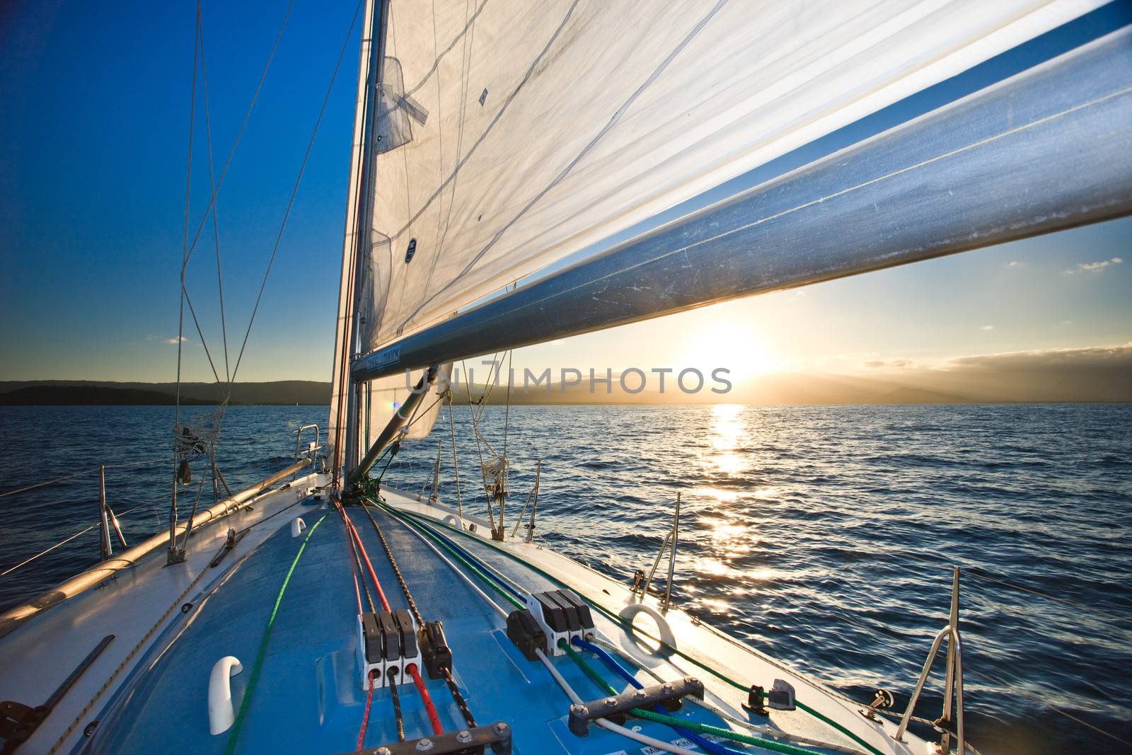 View from the deck of a yacht sailing on the ocean of the sun sinking below the horizon at sunset