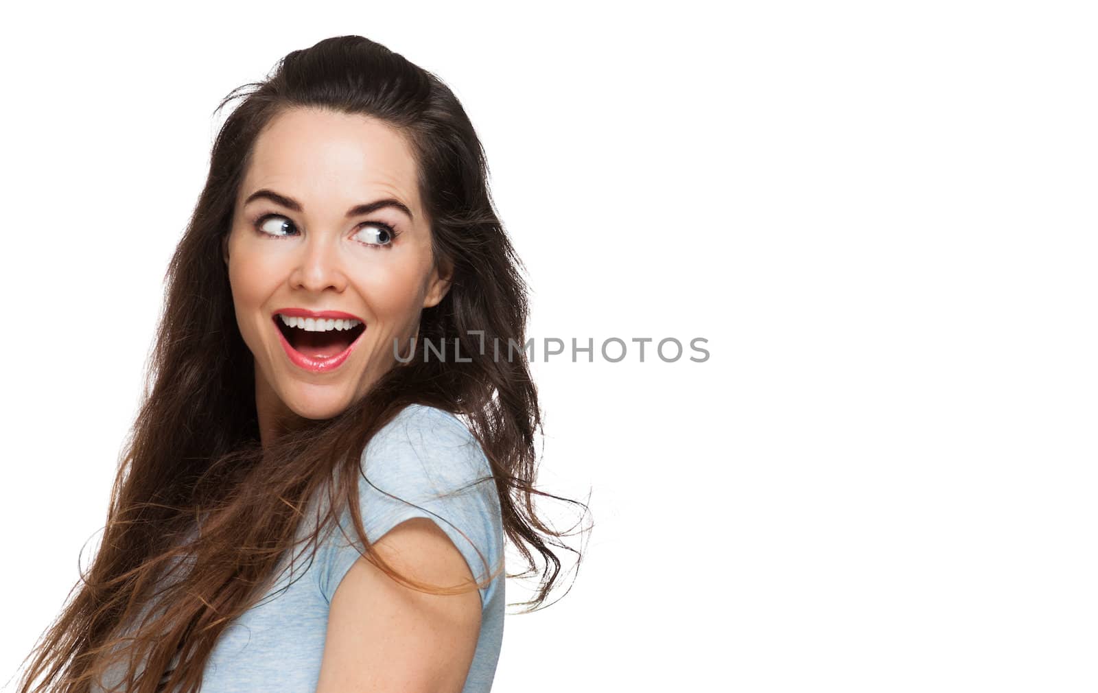 A happy surprised woman looking over her shoulder at copy-space. Isolated on white.