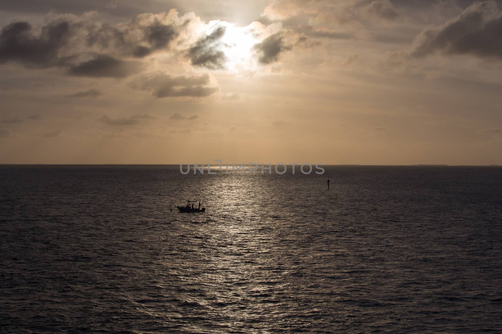 The Sun is setting over a solitary fishing boat on the Gulf of Mexico. This image was taken from the historic Seven Mile Bridge at Marathon Key in the Florida Keys.