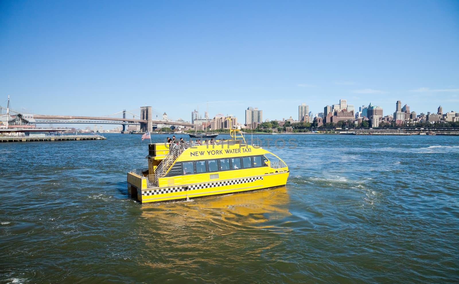 NEW YORK - SEPTEMBER 21: New York City Water Taxi with Brooklyn skyline and Brooklyn Bridge seen from Downtown on September 21, 2012. NYC Water Taxi has been servicing NYC commuters since 2002