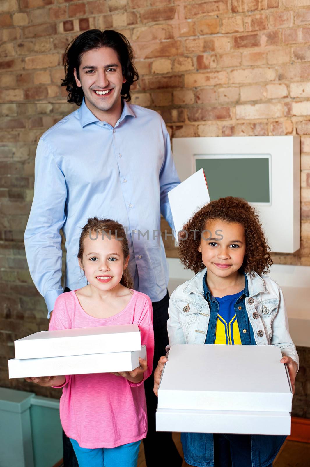 Little girls with their father holding pizza boxes