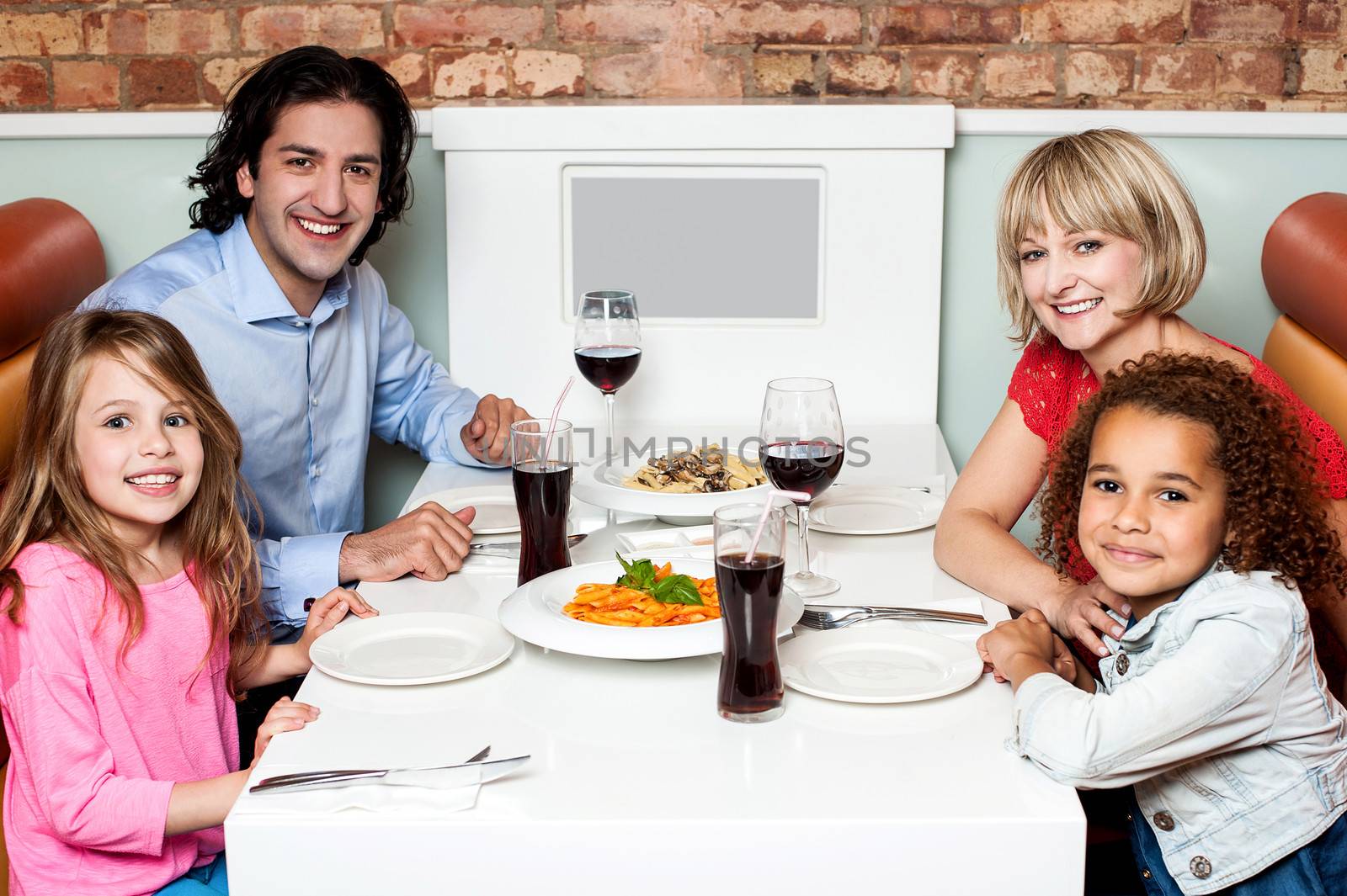 Cheerful family of four in a restaurant by stockyimages