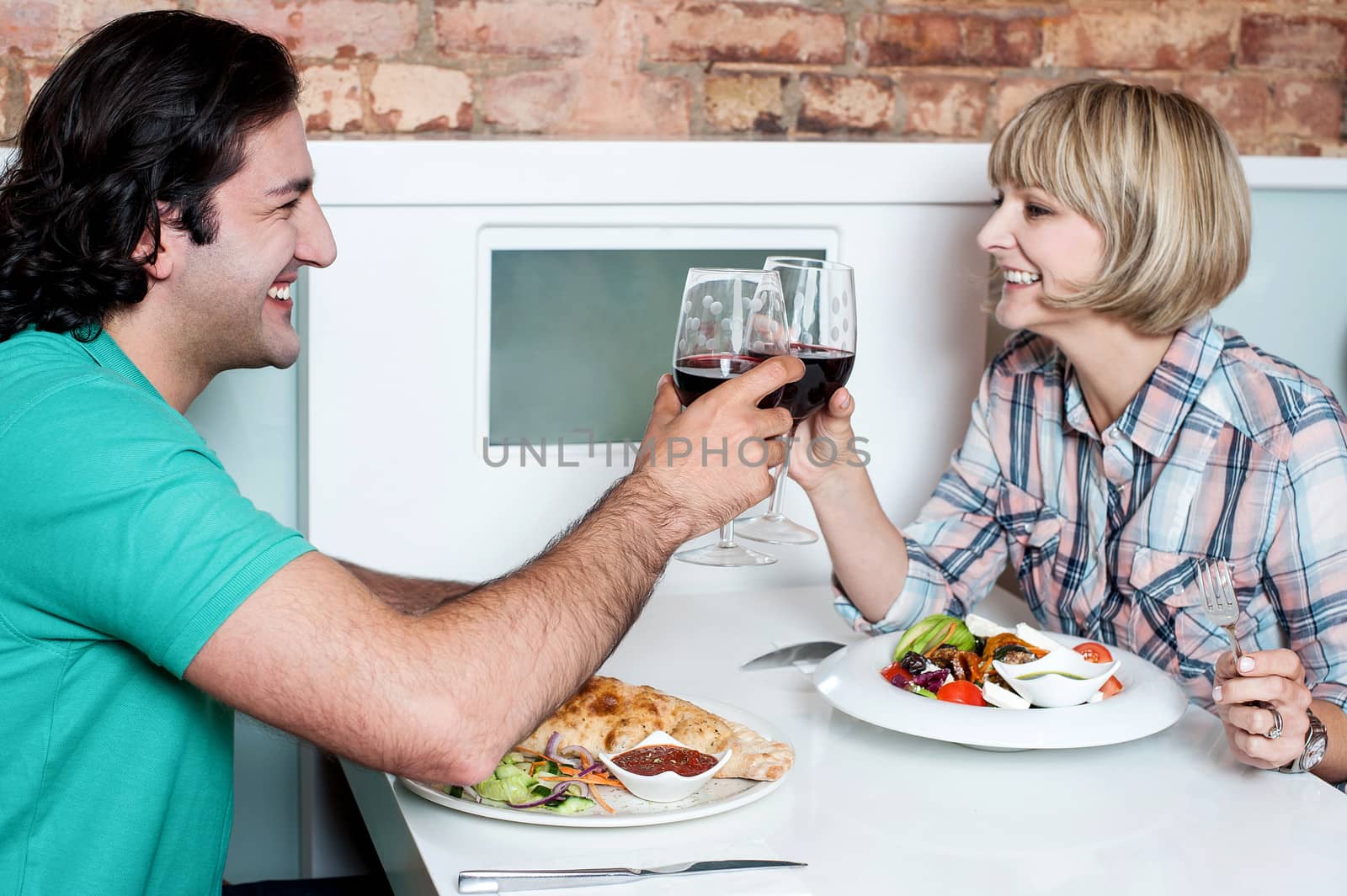Couple toasting over a restaurant table by stockyimages