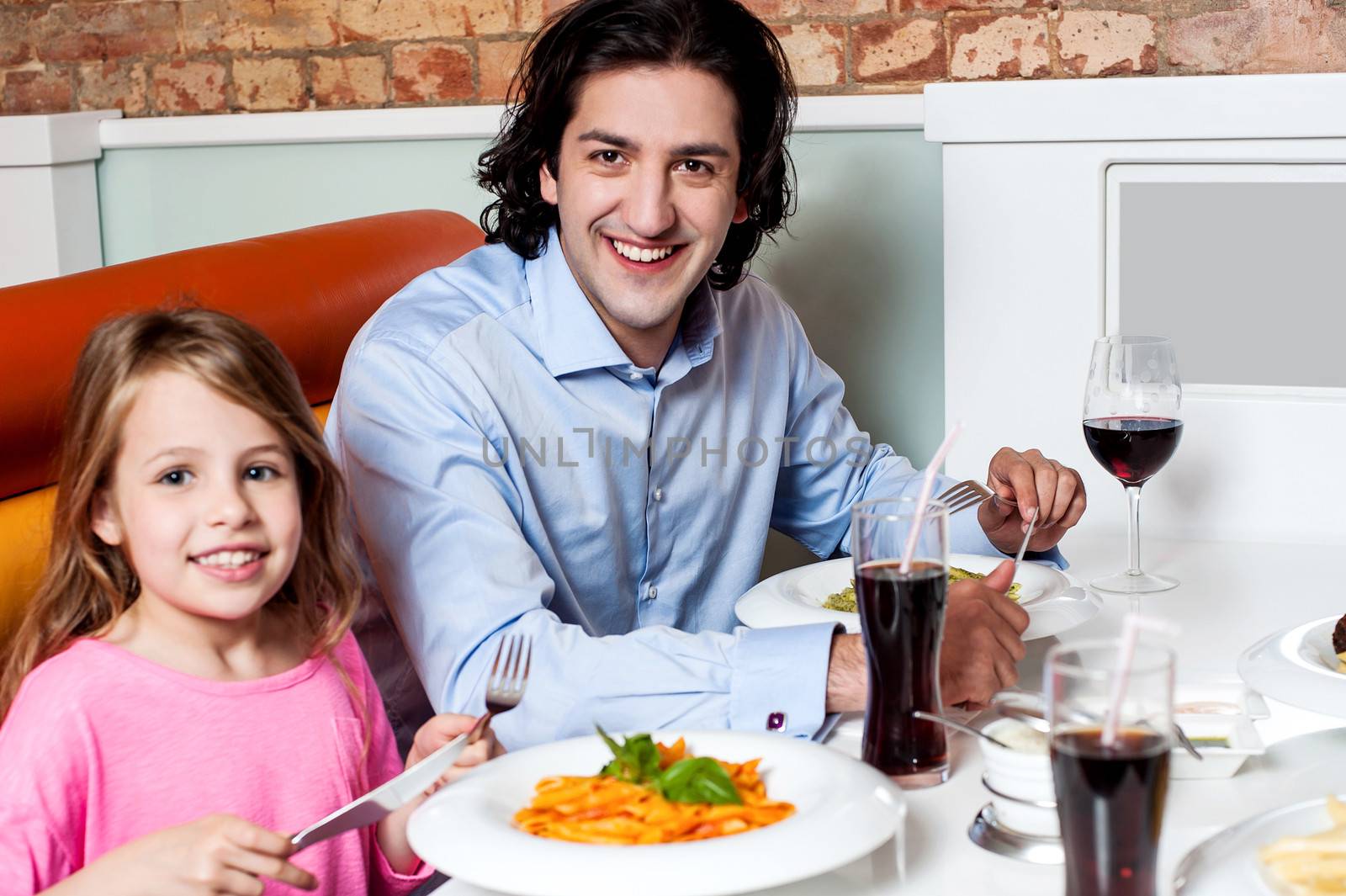 Little girl with her father at a restaurant by stockyimages
