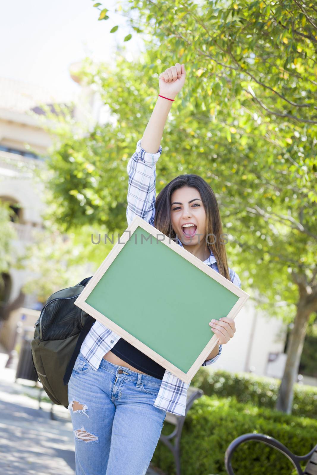 Excited Mixed Race Female Student Holding Blank Chalkboard by Feverpitched