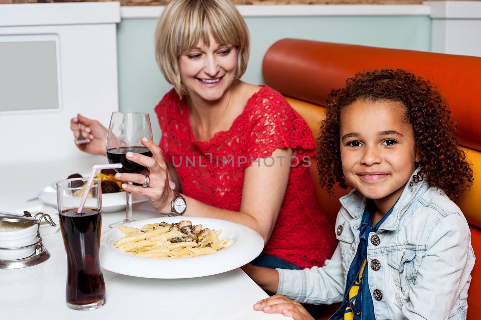 Little girl enjoying dinner with her mom by stockyimages