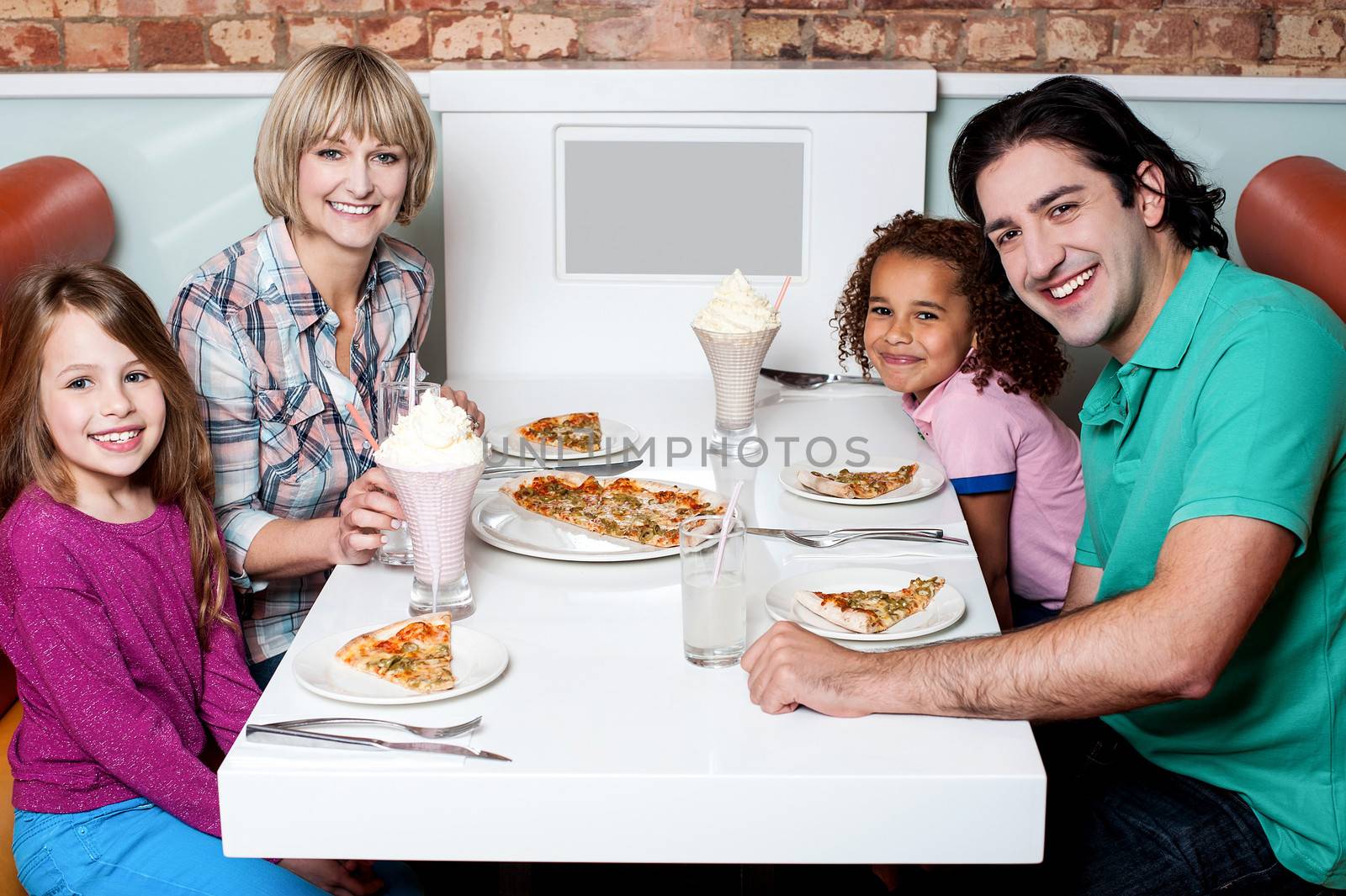 Cheerful family of four enjoying dinner by stockyimages