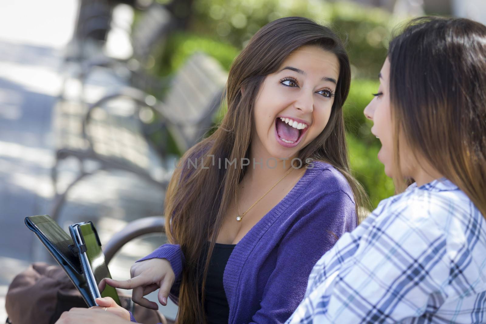 Two Happy Mixed Race Students Using Touch Pad Computer Outside Together on Campus.