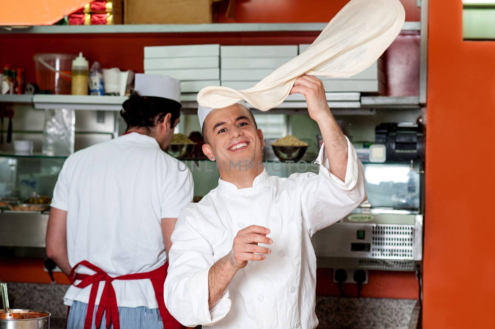 Chef throwing up thin base dough by stockyimages