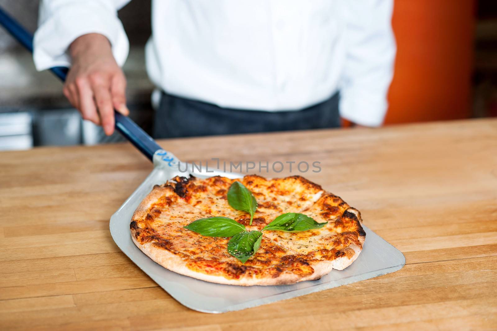Chef placing freshly baked pizza on the table