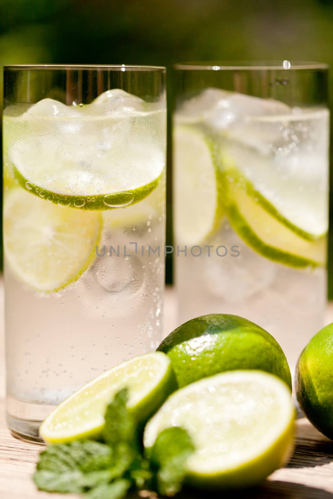 fresh cold refreshment drink mineral water soda with lime and mint on wooden table in summer