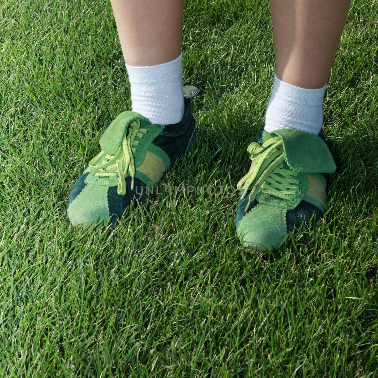 feet of woman dressed in green sports shoes on grass