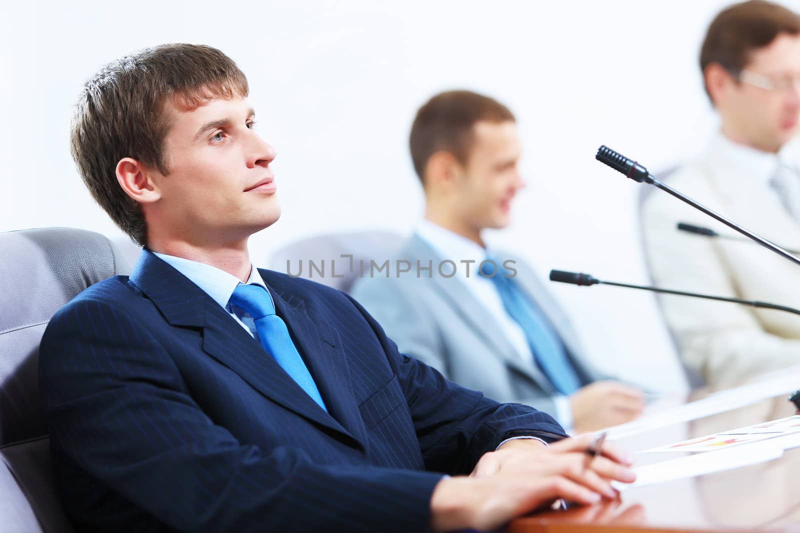 Image of three businesspeople at table at conference